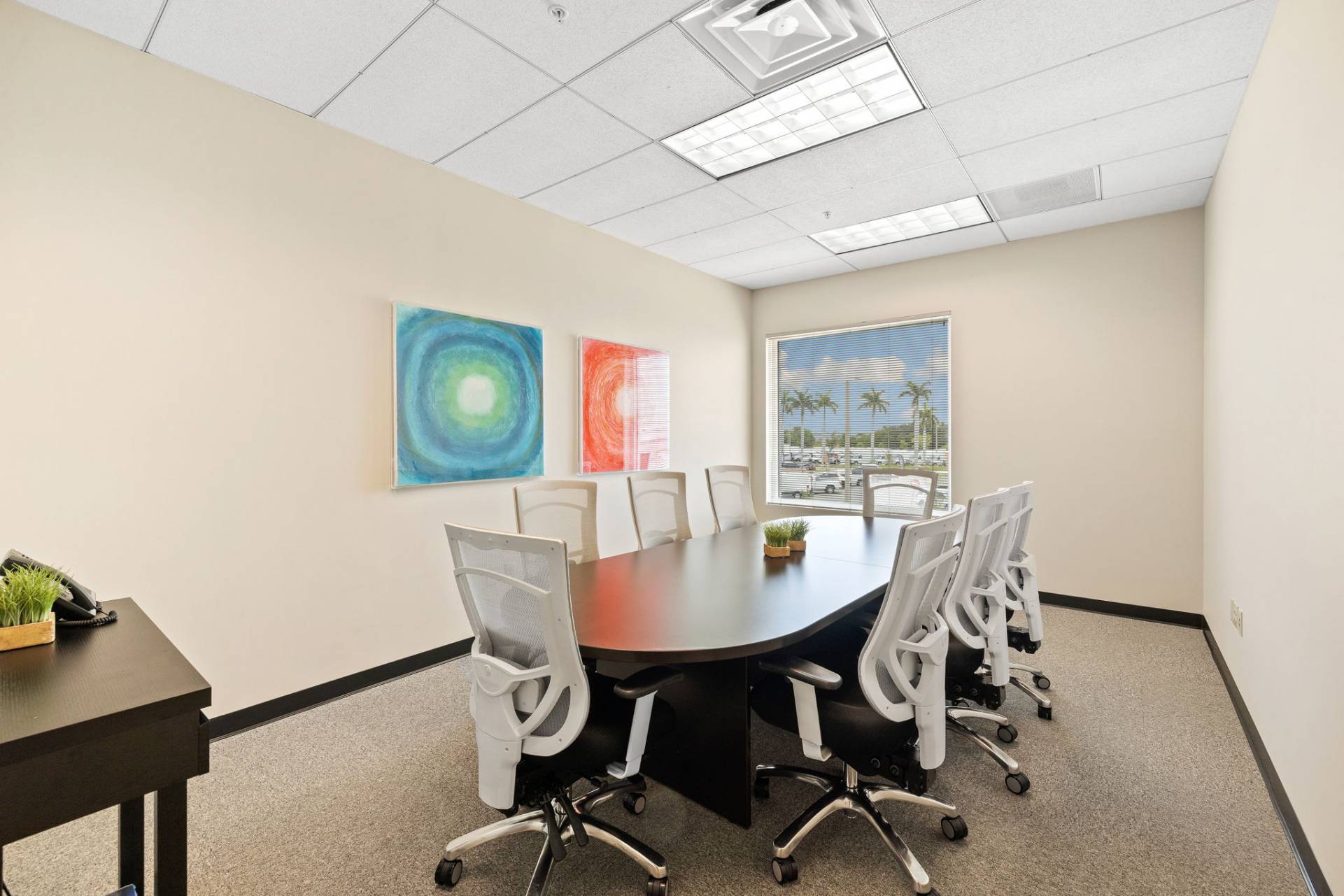 Second-floor conference room with 8-seat table, HDMI TV, VOIP phone, and private Wi-Fi. Fort Myers executive suites.