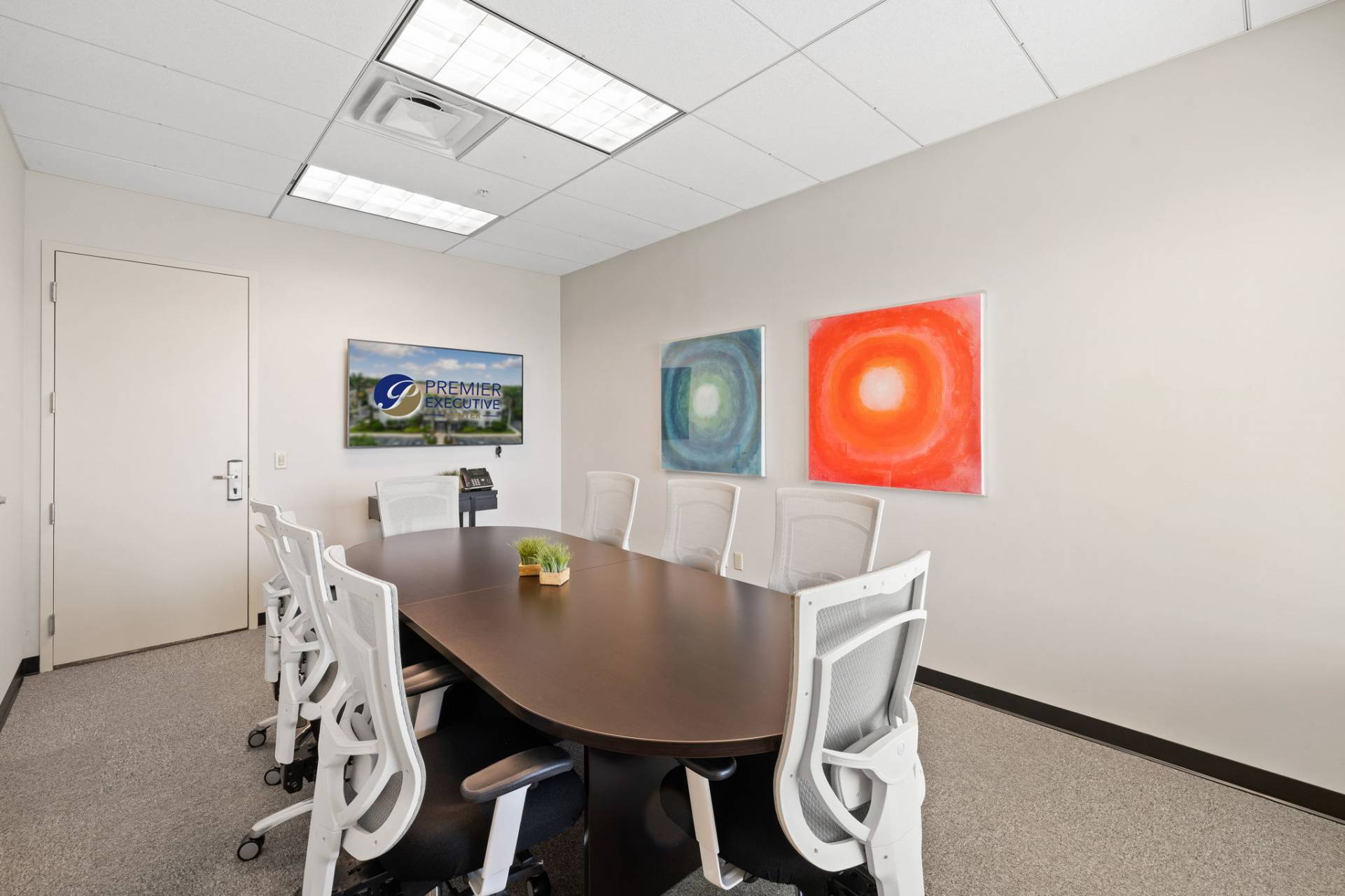 Second-floor conference room with 8-seat table, HDMI TV, VOIP phone, and private Wi-Fi. Fort Myers executive suites.