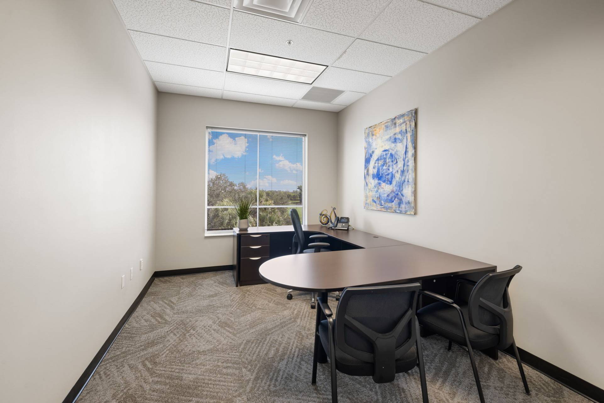 Second-floor conference room with 8-seat table, HDMI TV, VOIP phone, and private Wi-Fi. Fort Myers executive suites.